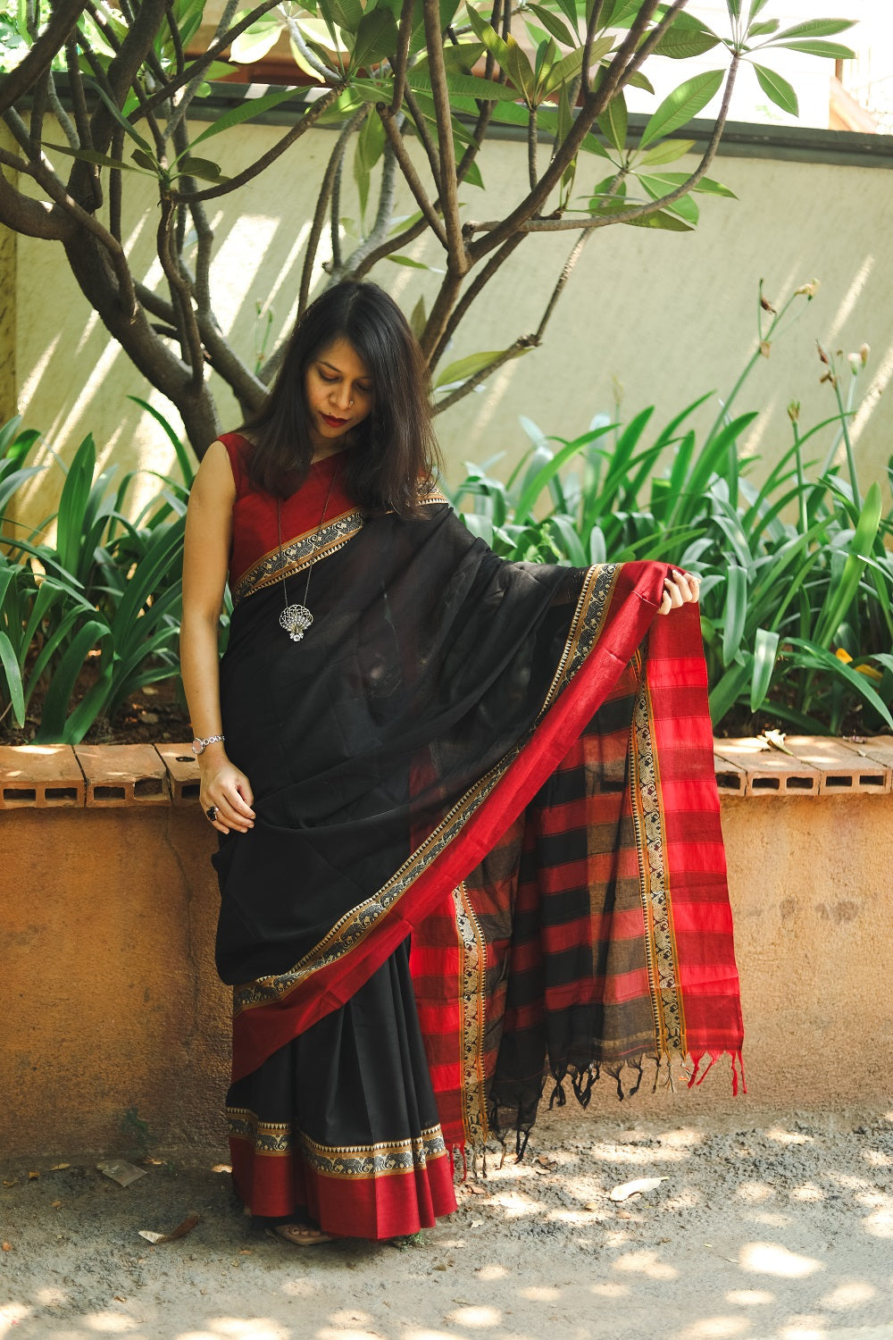 Woman in a black narayanpet handloom cotton saree looking down