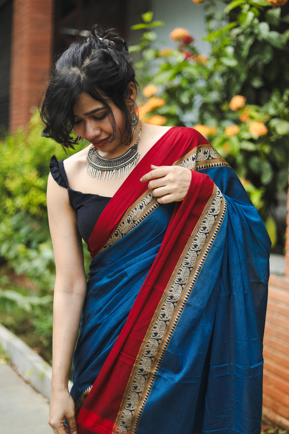 woman in blue narayanpet handloom cotton saree fixing her saree