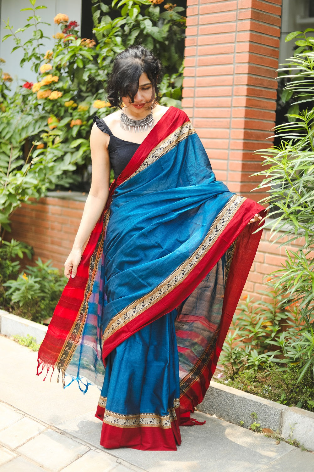 Woman in blue narayanpet handloom cotton saree looking down. full picture.