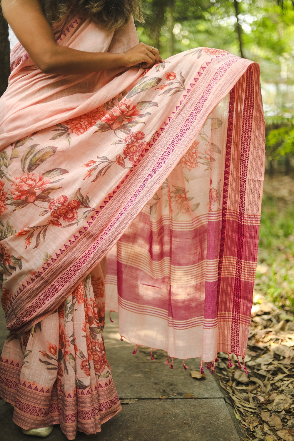Woman adjusting her pastel pink floral printed khadi cotton saree