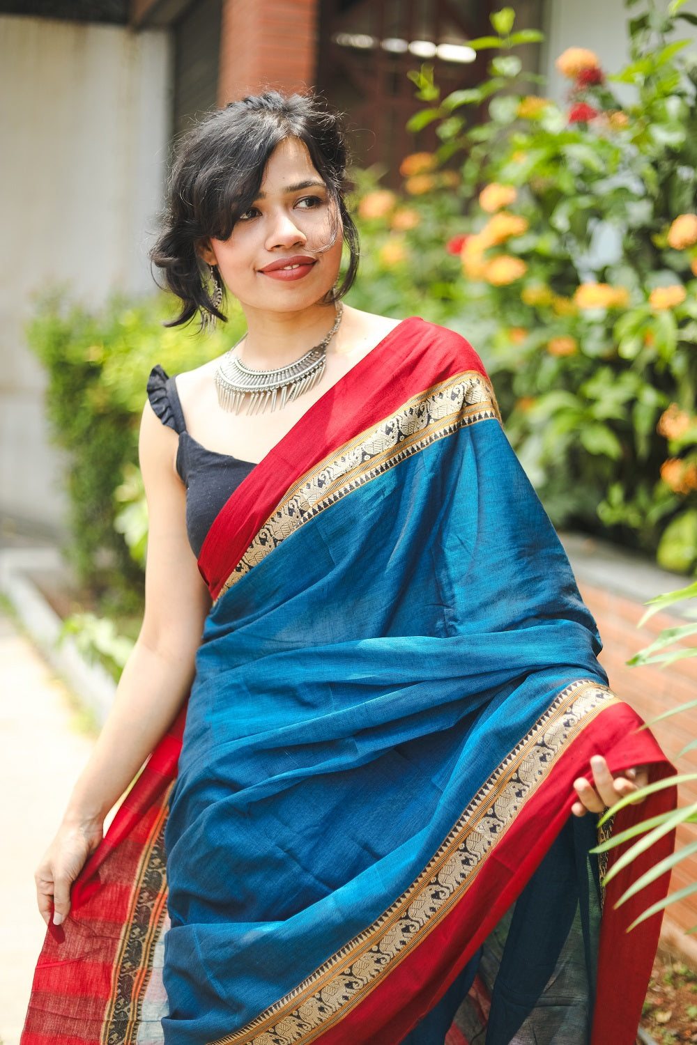 Woman in a blue narayanpet handloom cotton saree looking to the side