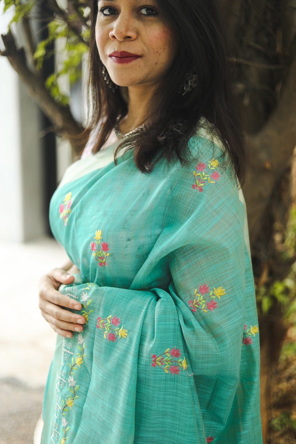 Woman in a blue linen cotton saree showing the embroidery on the sari