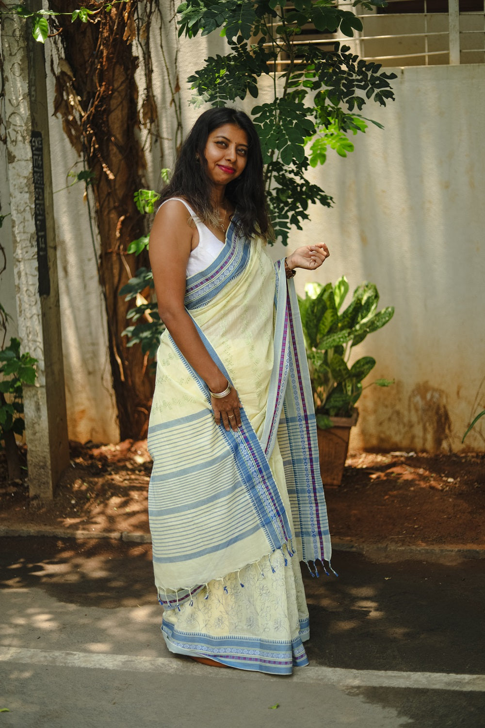 A woman wearing a light yellow cotton embroidered sari on the street