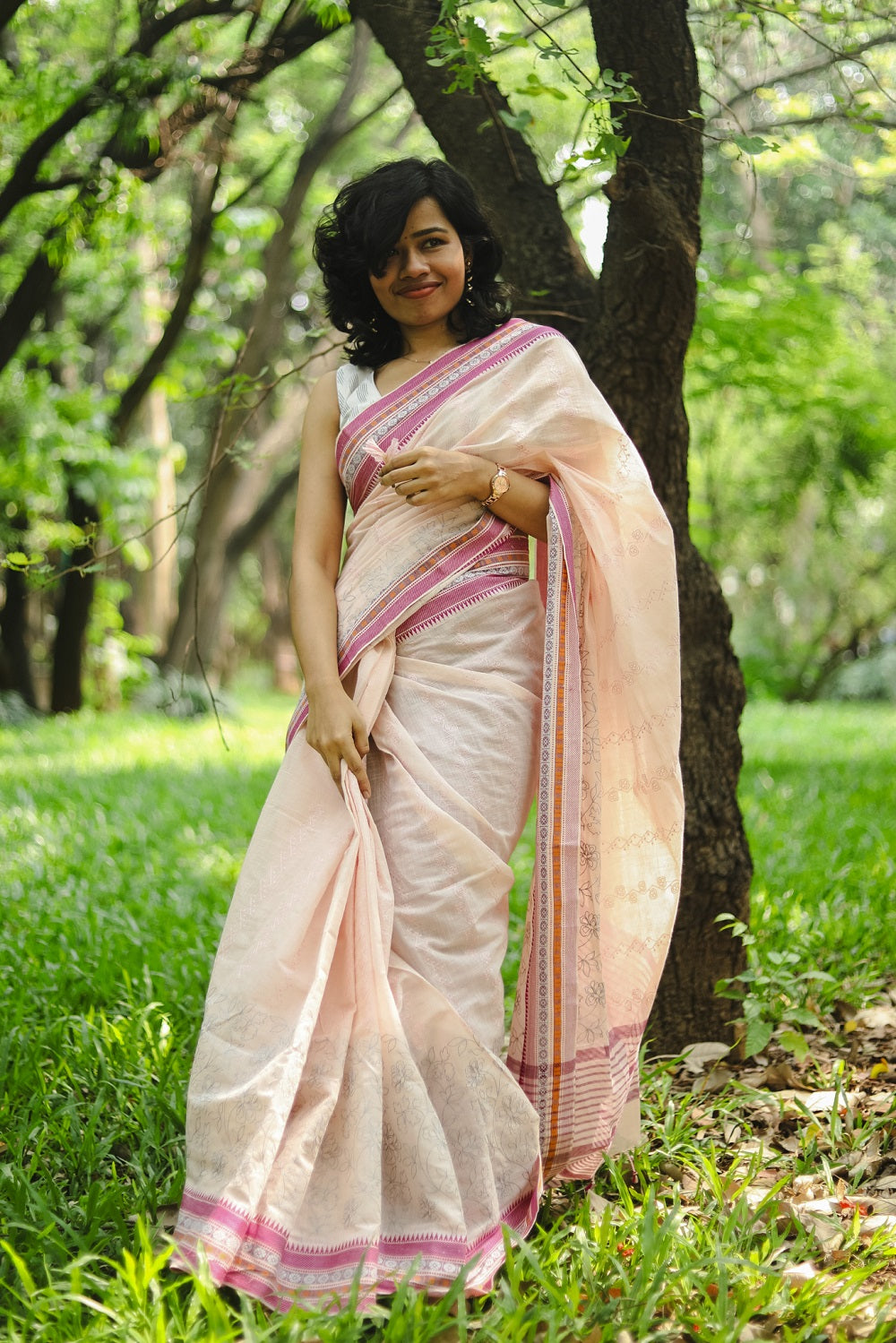 A woman in a pastel pink cotton embroidered saree