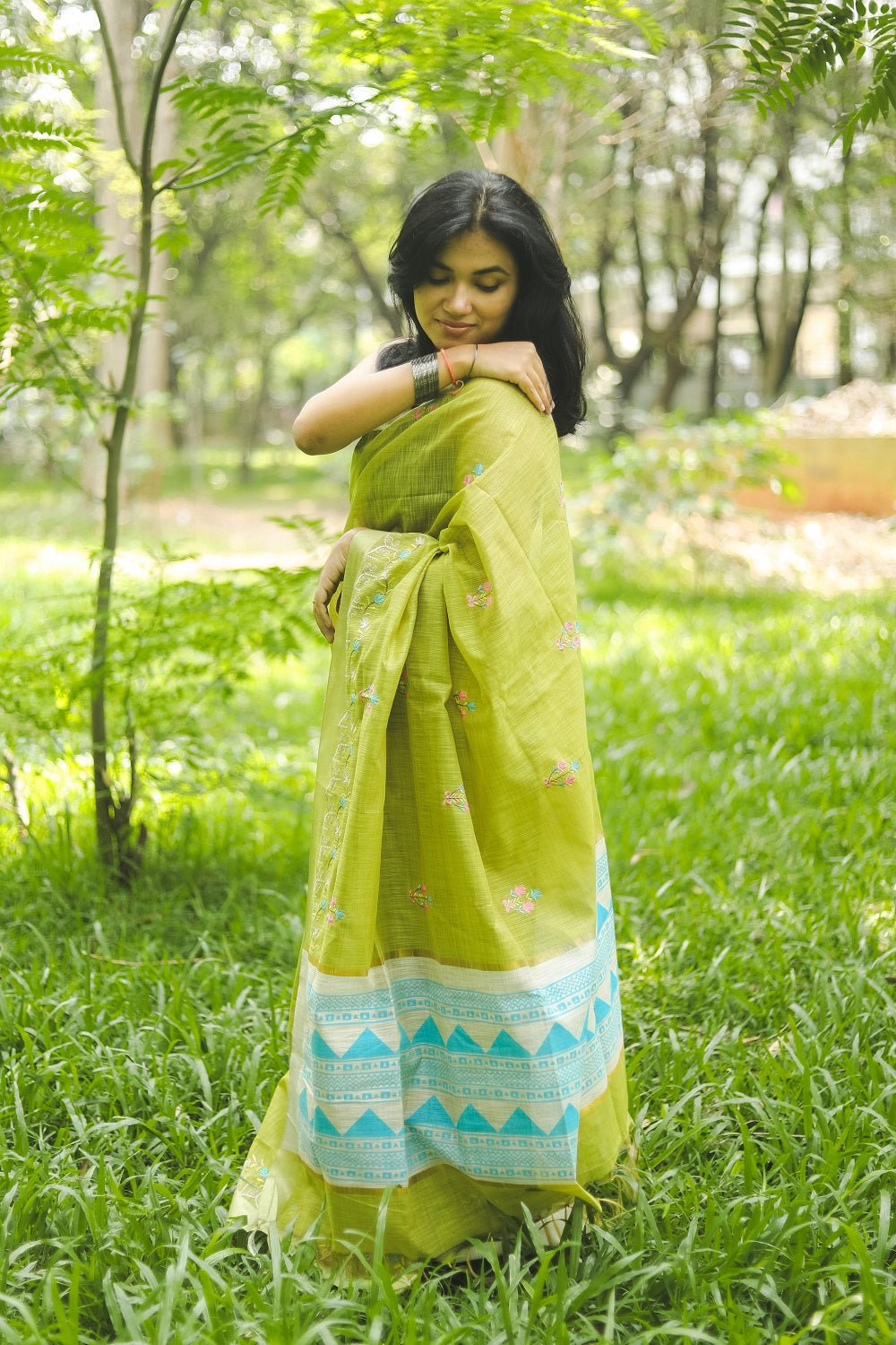 Woman in a vibrant green linen cotton saree adjusting her sari