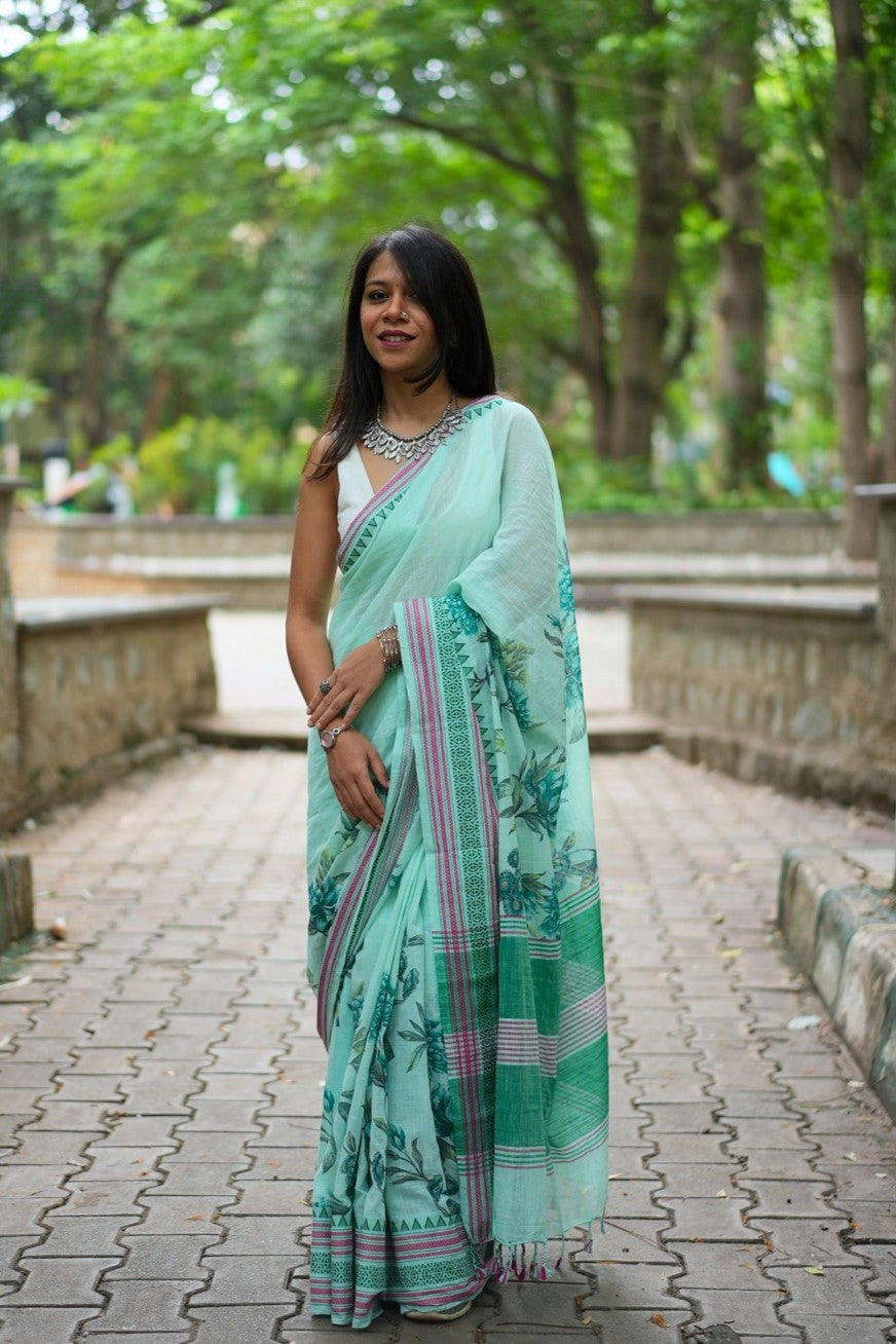 Woman in a pastel green floral printed khadi cotton saree posing for a picture