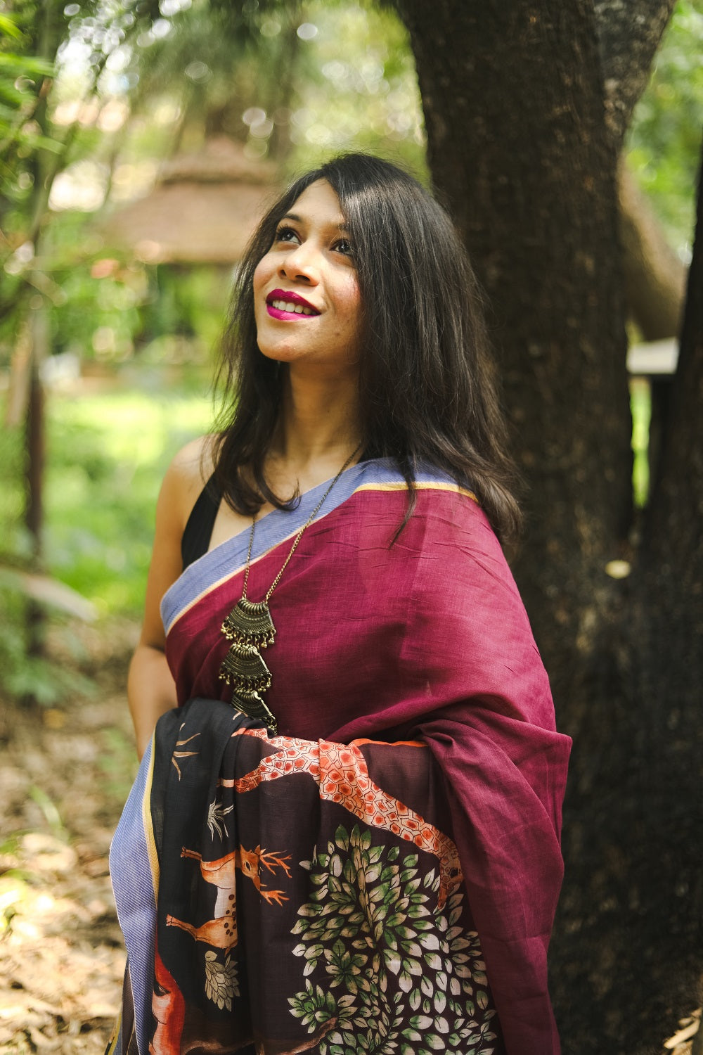 Woman looking up wearing a saree amidst nature