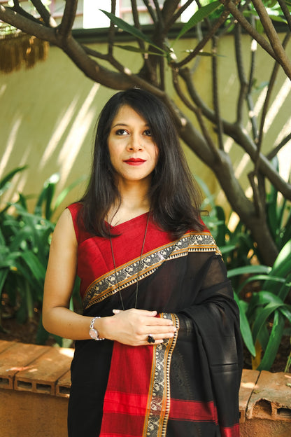 Woman in a black narayanpet handloom cotton saree posing