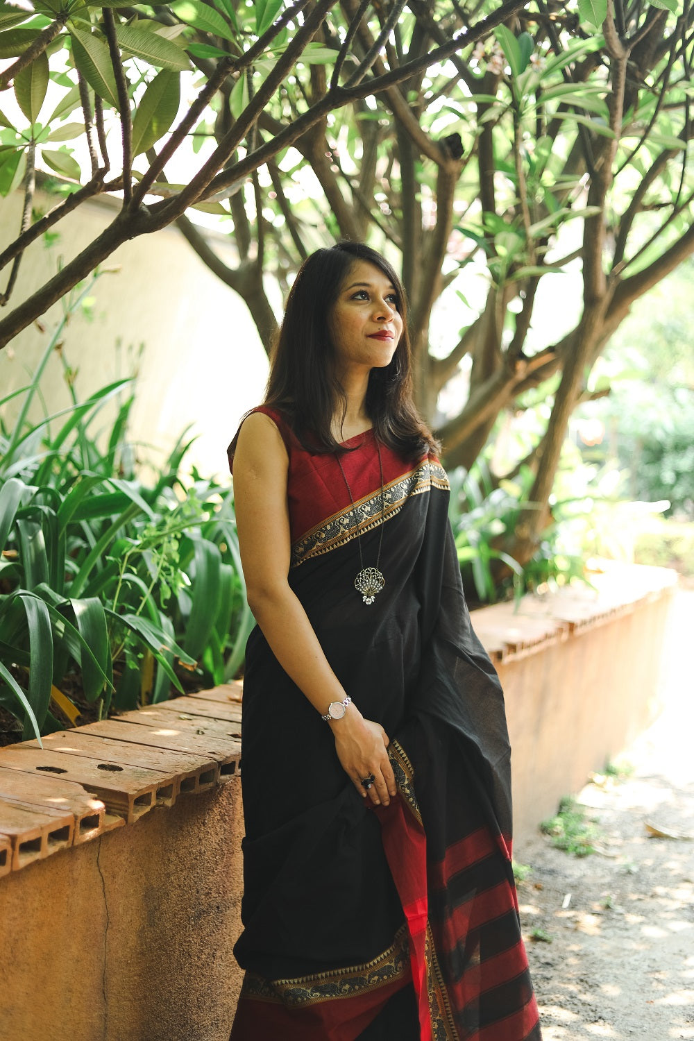 Woman in a black narayanpet handloom cotton saree looking up