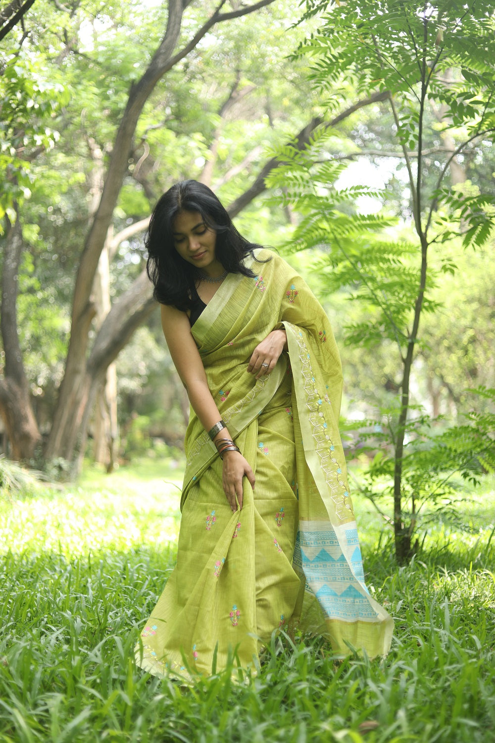 Woman in a vibrant green linen cotton saree adjusting her sari