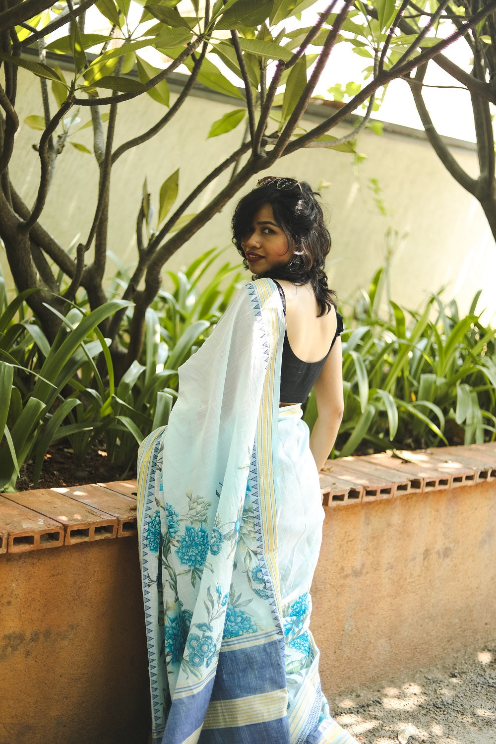 Woman in a pastel blue khadi cotton floral printed saree showing her pallu