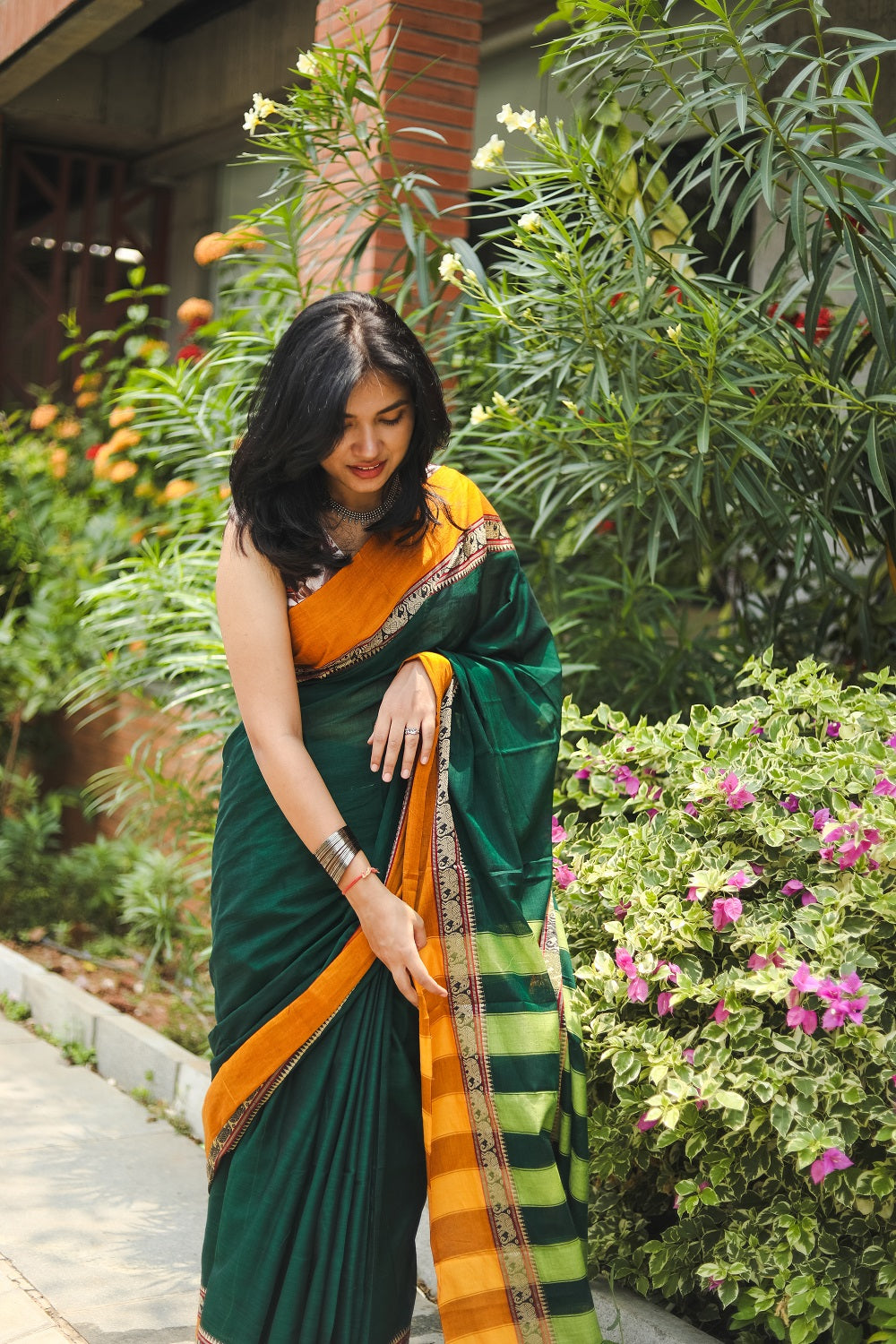 Woman in a green narayanpet handloom cotton saree playing with her saree