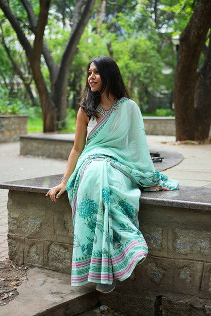 Woman in a pastel green floral printed khadi cotton saree sitting in a park