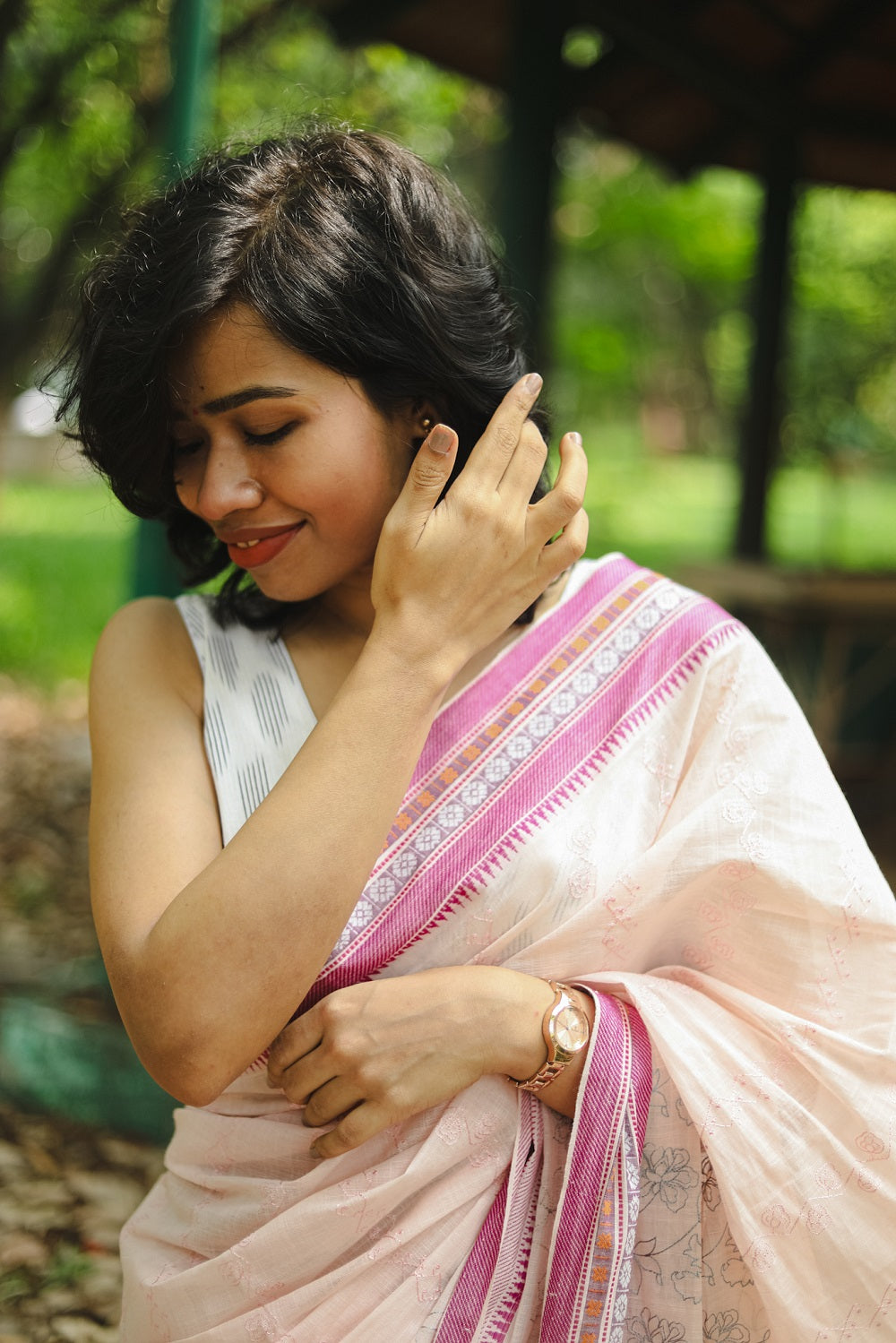 woman in a pastel pink cotton saree adjusting her hair