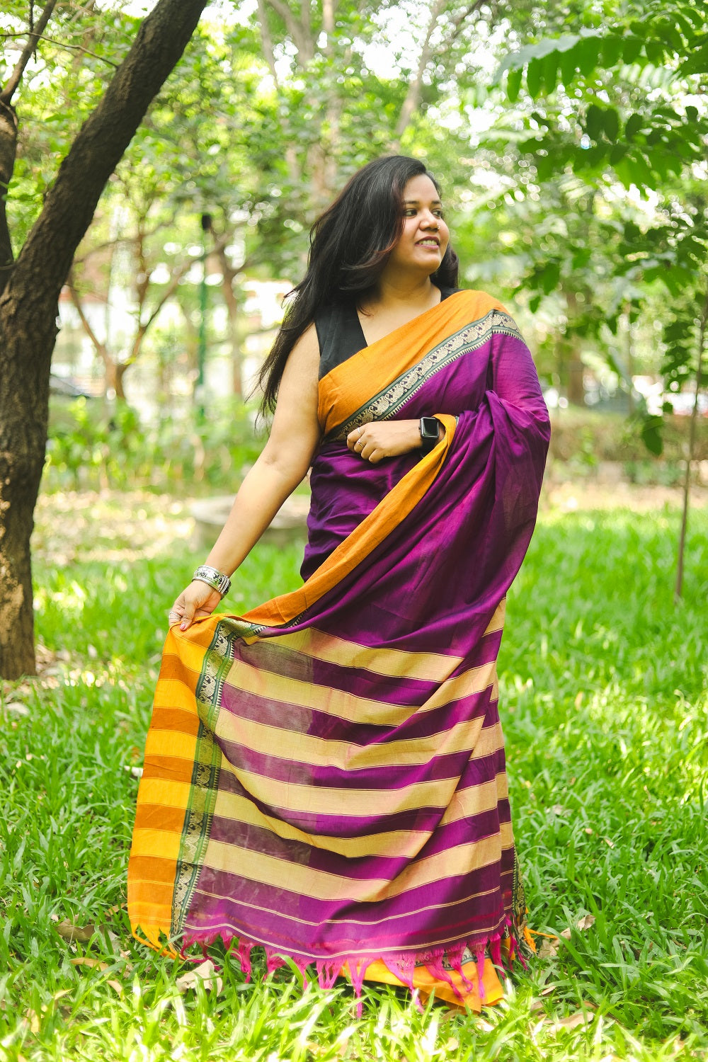 Woman in a purple narayanpet handloom cotton saree showing her pallu