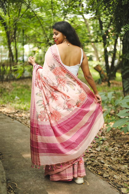 Woman in a pastel pink floral printed khadi cotton saree showing her pallu. This is shot from the back.